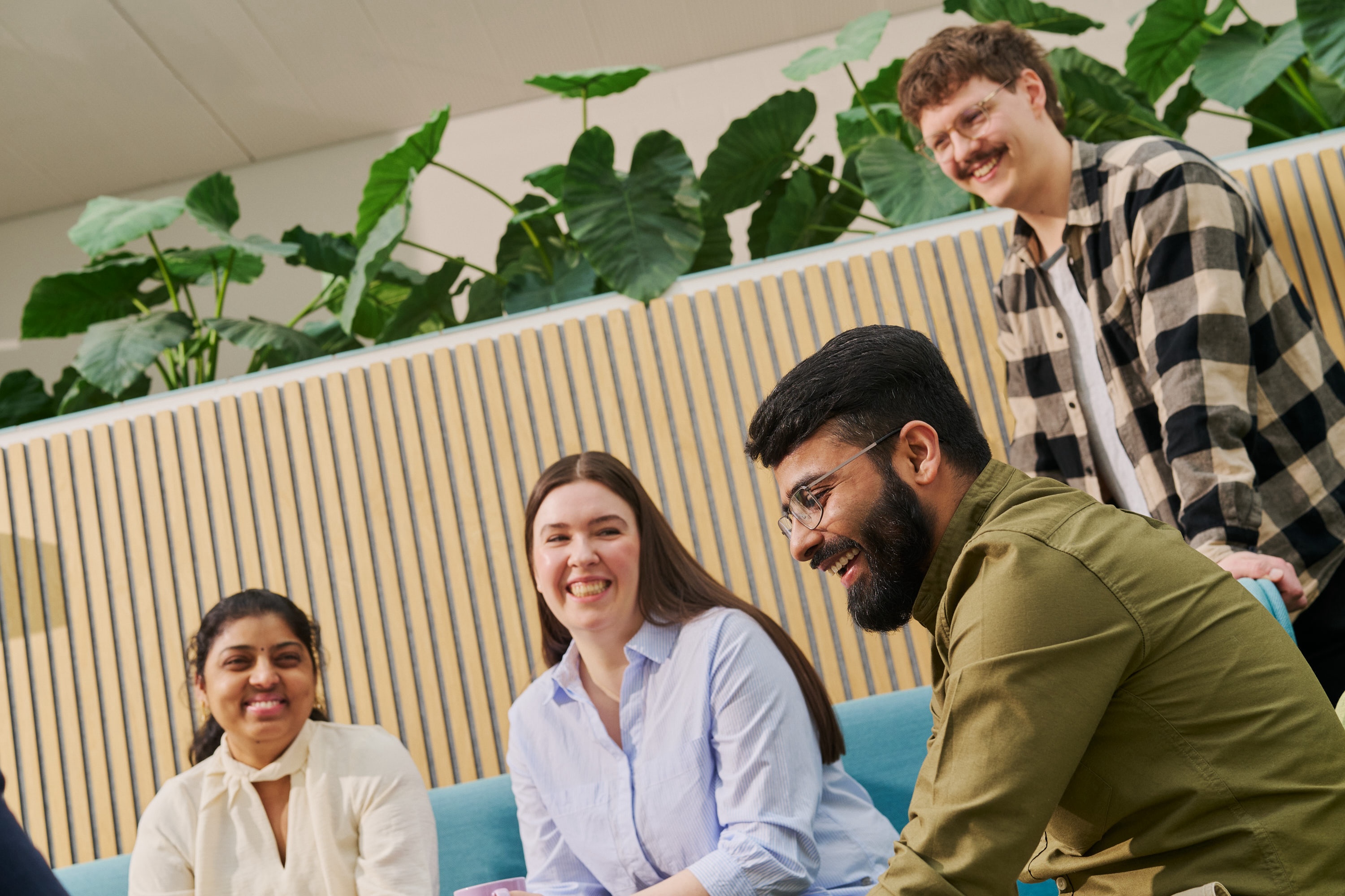 Four people in a lounge area smiling and discussing with each other.