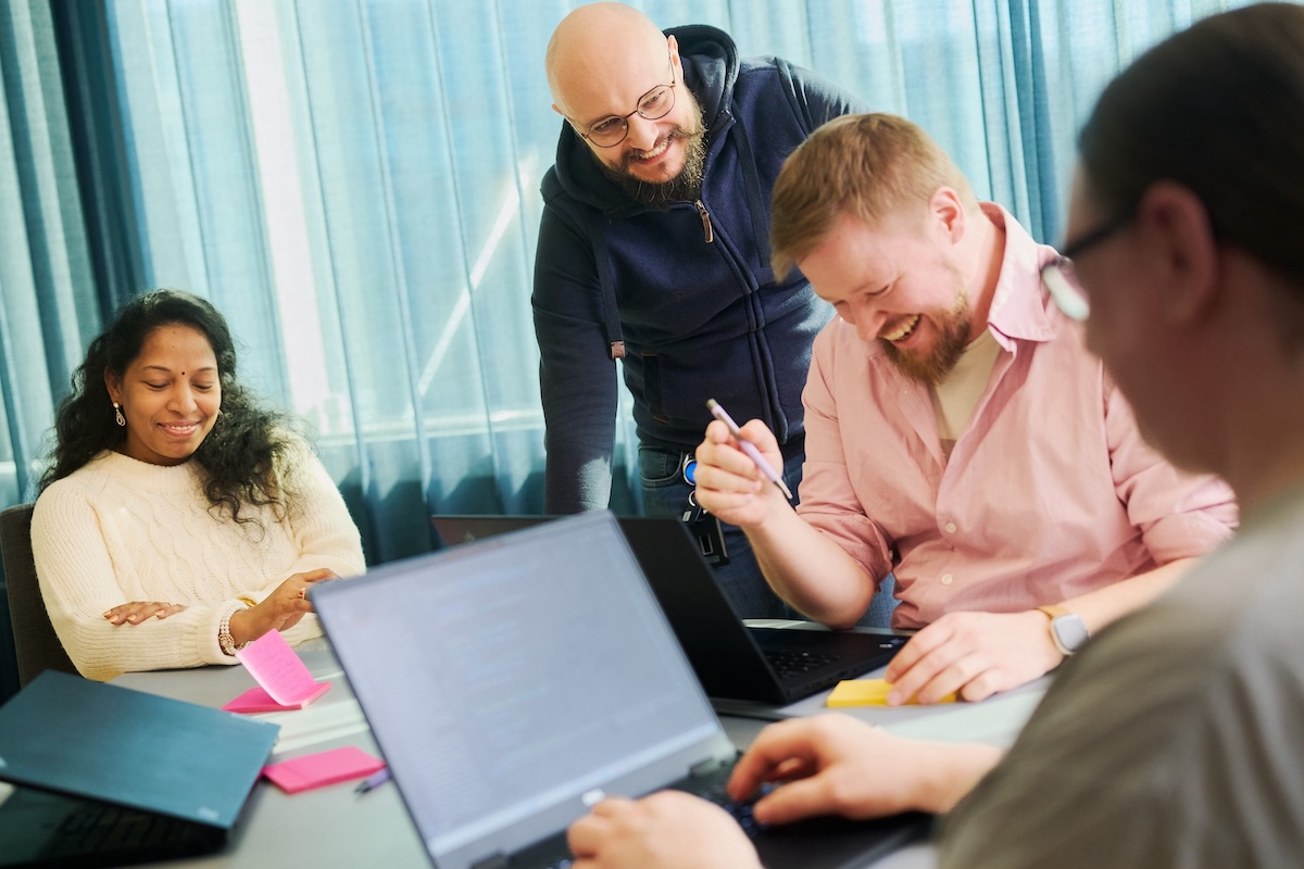 Four people sitting around the table in a meeting room and laughing